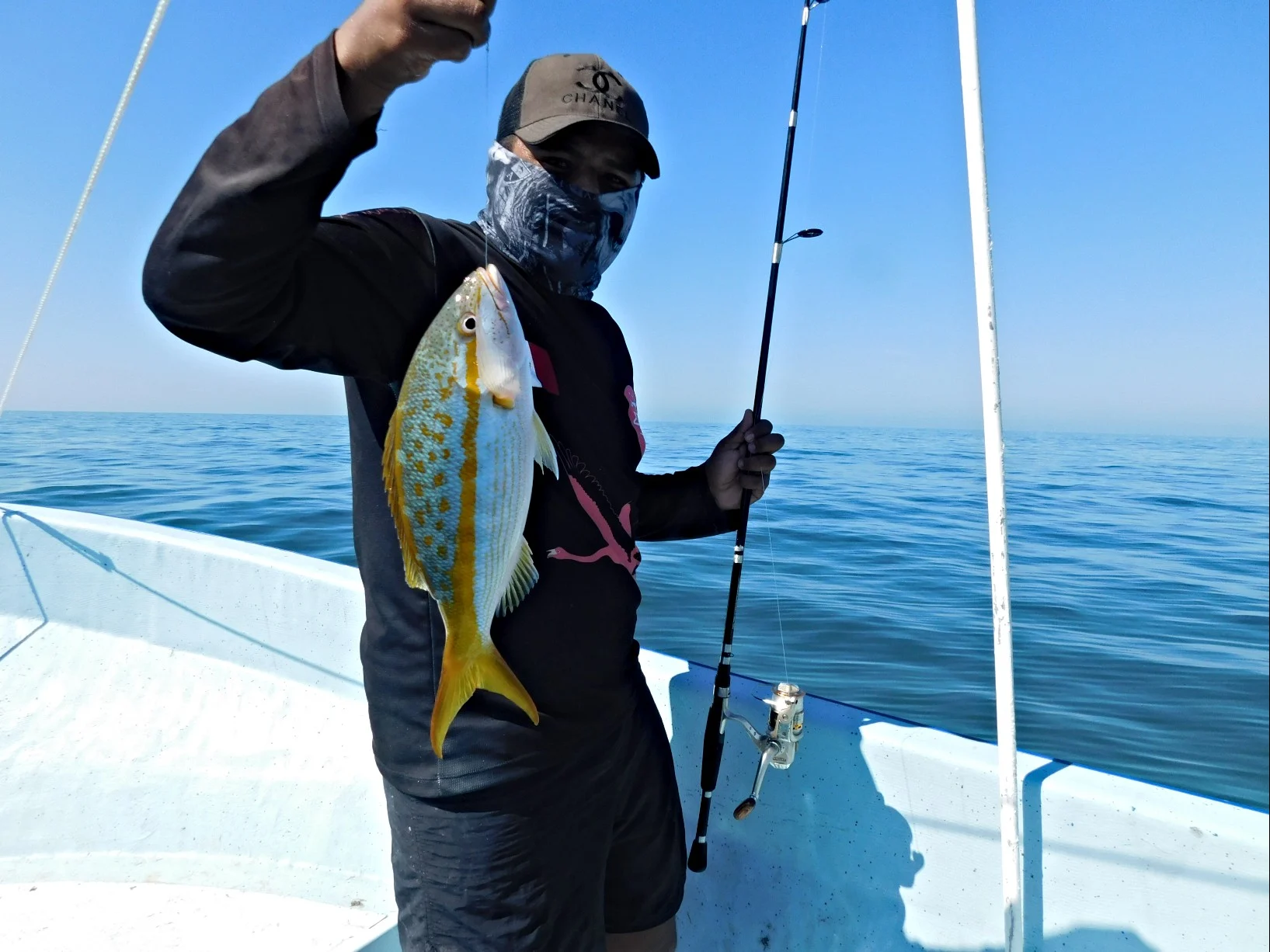 Pescador sosteniendo un pez recién capturado en lancha frente a Sisal
