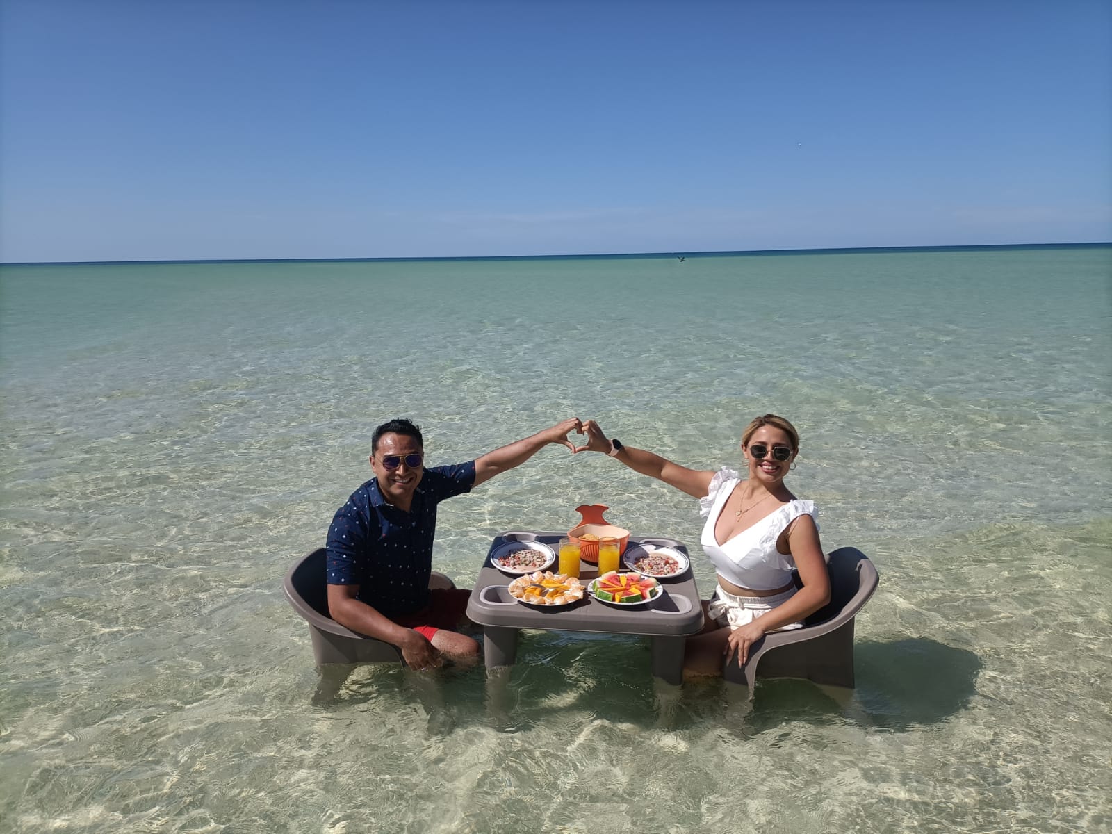 Pareja comiendo en una mesa flotante dentro del mar